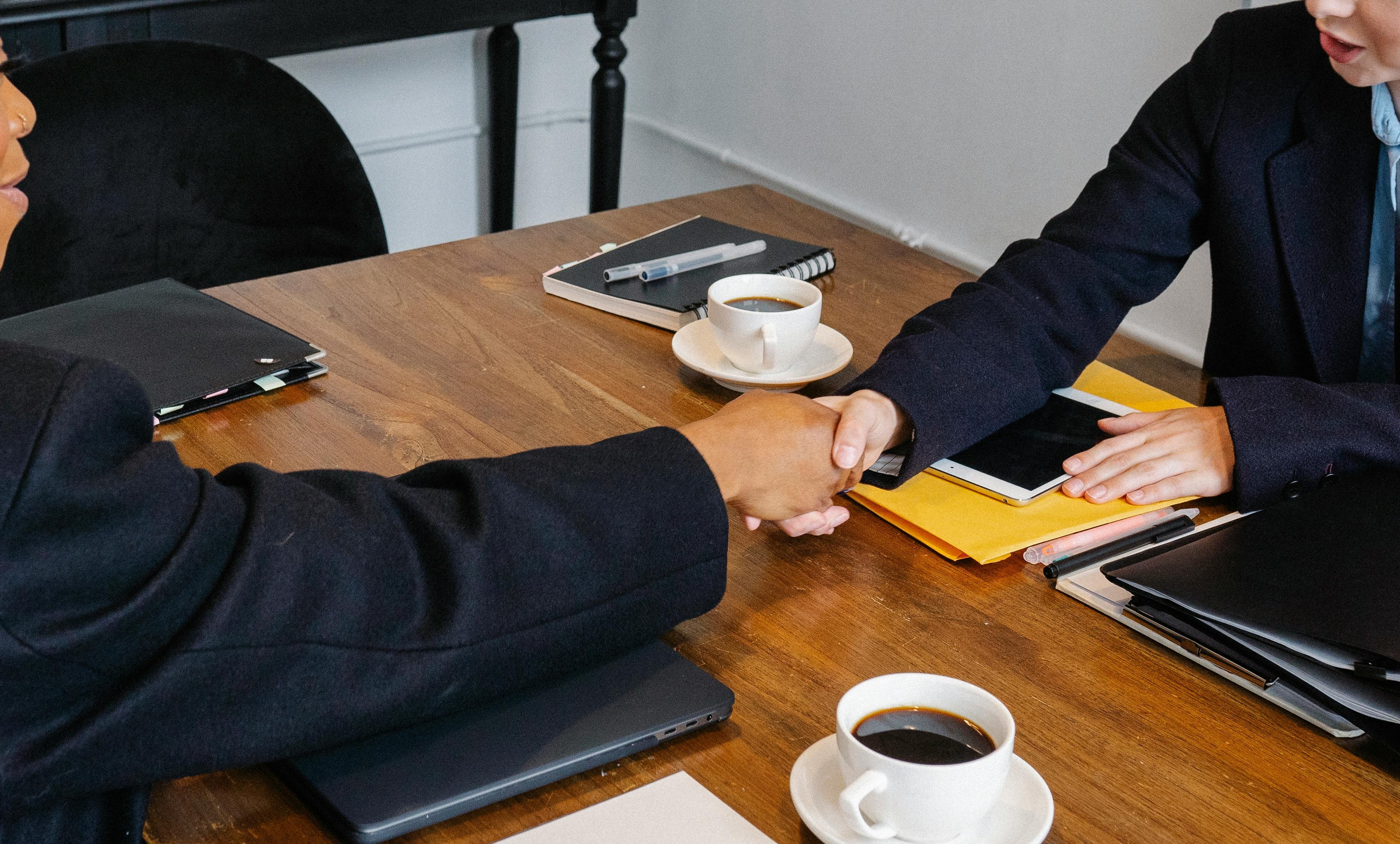 cheerful businesswomen shaking hands during meeting